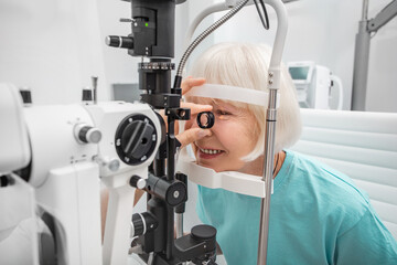 Elderly woman eyesight test with binocular slit-lamp. Checking retina of a female eye close-up. Ophthalmology Clinic - obrazy, fototapety, plakaty