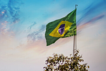 Bandeira do Brasil balançando ao vento com céu ao fundo. - obrazy, fototapety, plakaty