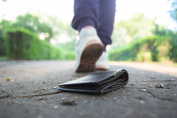 Lost wallet on the road and walking away woman. - obrazy, fototapety, plakaty