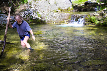 Adult hiker on an adventurous hike through the Gačnik canyon, photographs a magnificent waterfall, Soca valley, Slovenia, Europe