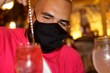 primer plano de barman con mascarilla medica preparando un cocktail