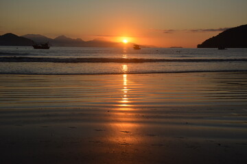 sol nascente, barco, paisagem laranja, relexo na água