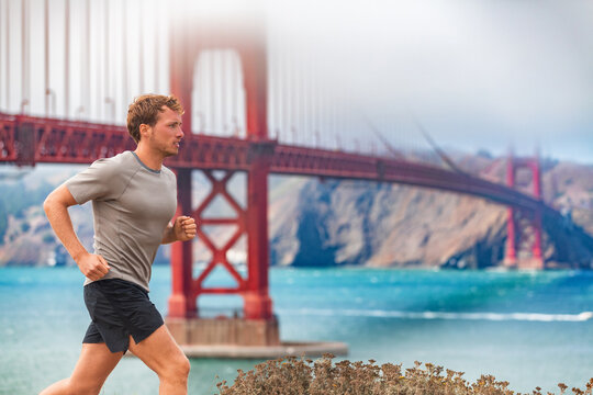 Man runner running by the Golden Gate Bridge in San Francisco, USA. Sports male athlete jogging training outdoors in autumn by scenic landscape.