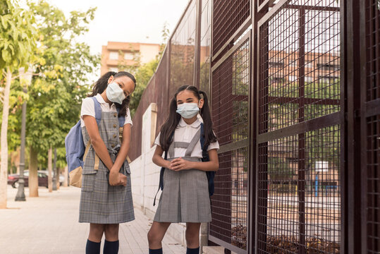 Two Fashion Girls Wearing School Uniform And Surgical Mask During Coronavirus Infection. Concept Of Back To School With Covid.