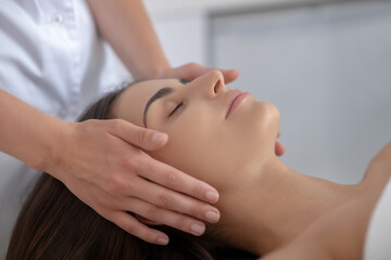 Obraz na płótnie Canvas Young pretty woman lying and having face massage