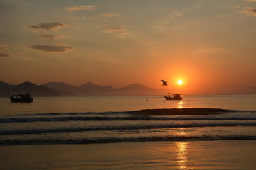 silhouette of fishing boat during sunrise on the beach, Itagua Ubatuba
