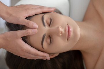 Obraz na płótnie Canvas Professional massage therapist massaging forehead of a woman