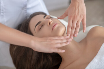 Professional massage therapist massaging face of a woman