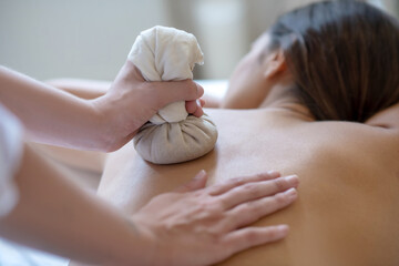 Young dark-haired woman having bags ayurvedic massage