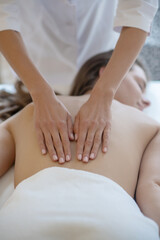 Obraz na płótnie Canvas Massage therapist in lab coat gently rubbing womans back
