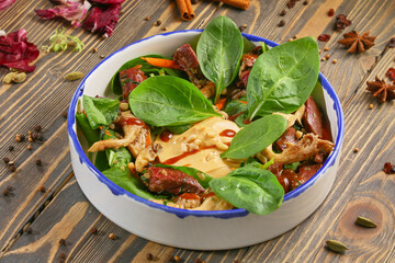 Salad of fresh vegetables, fried beef and oyster mushrooms is on the plate.