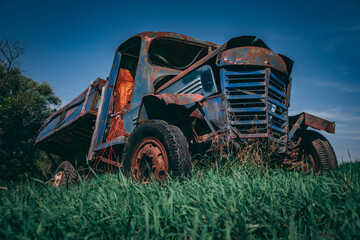 Old rusted truck falling apart in green grass. Retro truck in the middle of a field