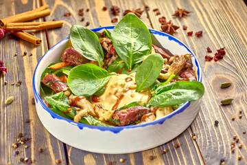 Salad of fresh vegetables, fried beef and oyster mushrooms is on the plate.