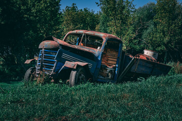 Old rusted truck falling apart in green grass. Retro truck in the middle of a field