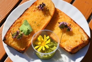 Goldgelbes Knoblauchbrot mit Dipp und essbaren Blüten