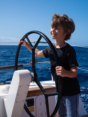 Young boy at the helm of a sailing boat
