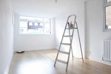 ladder with paint pot and brushes standing in empty room