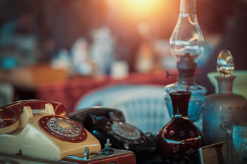 Vintage telephones, oil lamps, vases and bottles on the countertop at the sunday flea market. Shopping at antique bazaar.