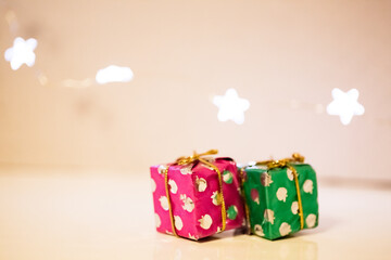 Obraz premium Two small gift boxes wrapped in festive Christmas paper lie on the table, and a garland of lights in the shape of stars