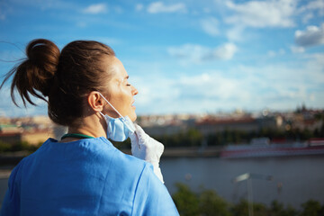 relaxed physician woman breathing outdoors in city against sky