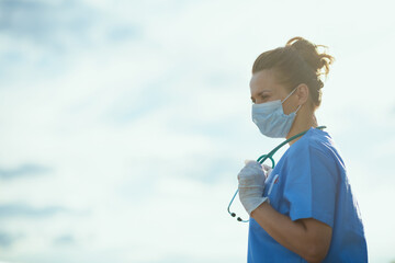 pensive modern medical practitioner woman outside against sky