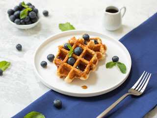 Homemade waffles with blueberries on the white background with a blue napkin. Selective focus.