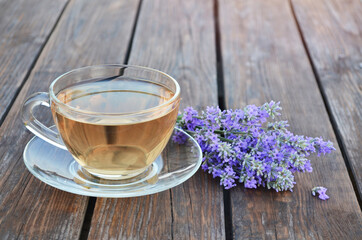 Cup of healthy hot lavender tea and bouquet of flowers a wooden table. Concept of a healthy lifestyle.