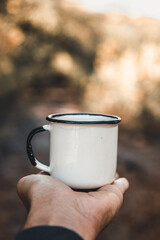 hand holding cup of coffee on natural background