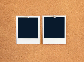 Blank square Instant pictures pinned to a corkboard  with metal pushpins.