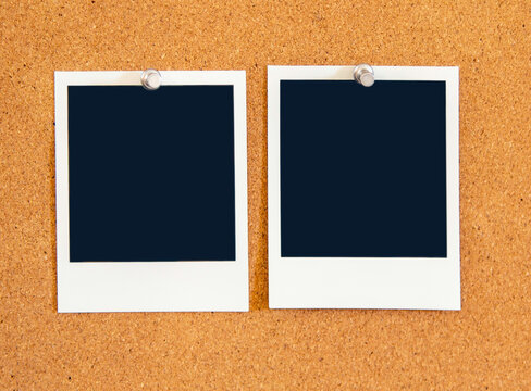 Blank square Instant pictures pinned to a corkboard  with metal pushpins.
