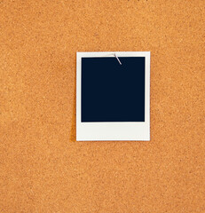 Fototapeta premium A Blank square instant picture pinned to a corkboard with a metal t-pin pushpin.