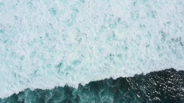 Top aerial view of giant ocean waves crashing and foaming. Amed, Bali