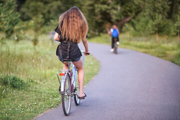 Fototapeta premium A girl riding a bicycle in a park in summer in the sunny morning.