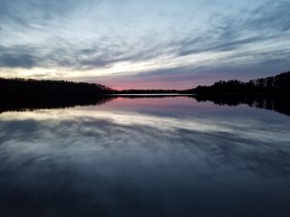 Placid Lake Reflecting Cloudy Sky Under Pink Horizon