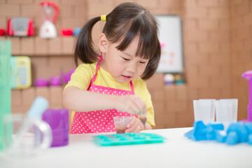 young girl making sweet gems for homeschooling in the kitchen build by cardboard