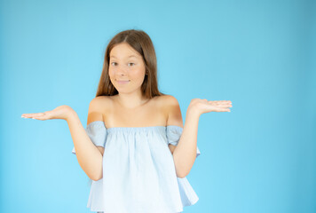 Smiling girl with doubtful gesture on blue background