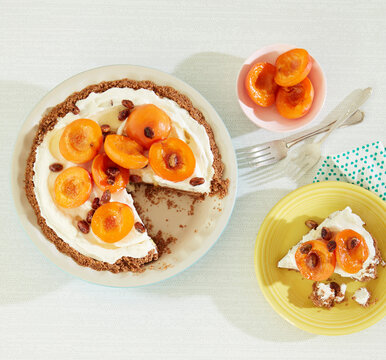 Overhead view of orange and honey cheesecake with apricots on table