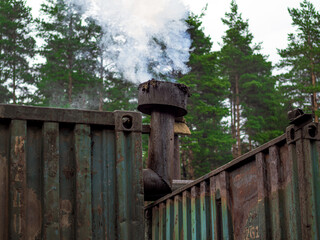 Smoke from the container pipe. Green forest background