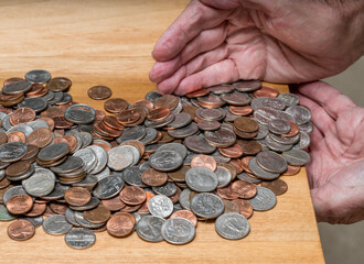 Hundreds of US coins being gathered into hands on wooden table as concept for hoarding during shortage of loose change © steheap