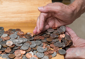 Hundreds of US coins being gathered into hands on wooden table as concept for hoarding during shortage of loose change © steheap
