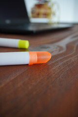 Colored markers next to a laptop on a wooden table