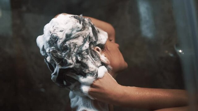 A woman washes short hair with shampoo in the shower cabin_02