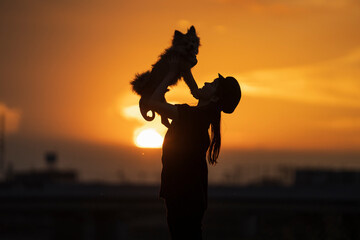 夕日と抱っこされる犬