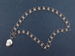 Fototapeta na wymiar Luxury elegant silver necklace with baroque pearl pendant on blue background