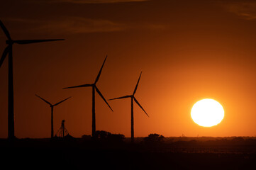 sun setting behind a group of wind turbines