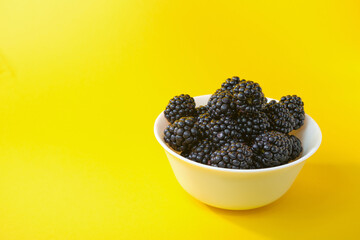 Dewberry. Blackberries in a wooden bowl on a light table. Fresh blackberries in a bowl close-up. Space for text