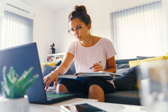 Front View On Young Caucasian Woman Study In Front Of The Laptop Computer At Home - Girl Reading Book Preparing Exam Test Having Online Consultation - Education And Learning Concept