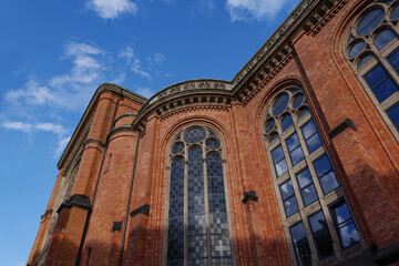 Fototapeta na wymiar Outdoor sunny and low angle view of Protestant Church with old rough beautiful vintage brick and tall windows and ornament glass in Germany