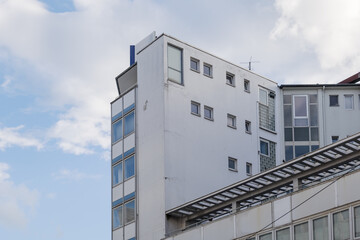 Outdoor sunny view, detail at corner of exterior facade with rectangular windows and rooftop of typical modern office building. 