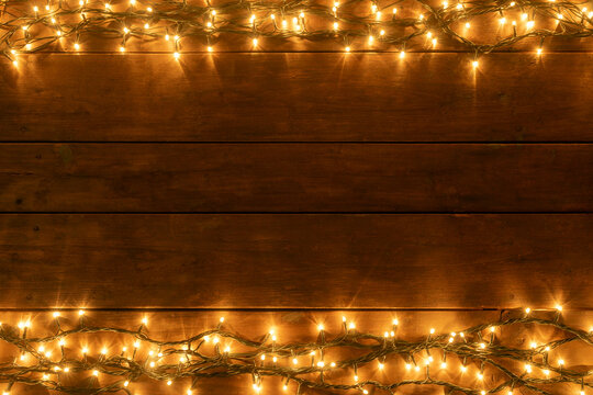 BROWN WOODEN PLANK AND WARM LIGHTS ABOVE AND BELOW. COPY SPACE FOR TEXT. RUSTIC CHRISTMAS ADVERTISEMENT CONCEPT